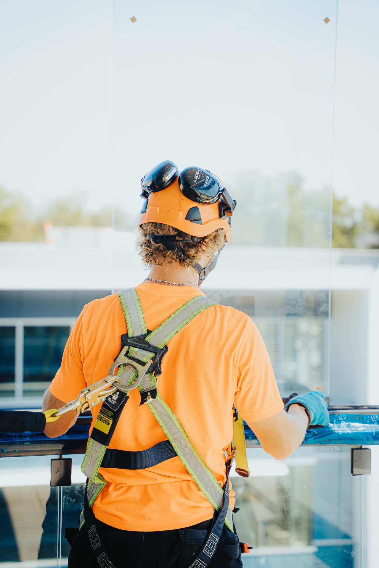 Installer in safety harness working on a glass railing