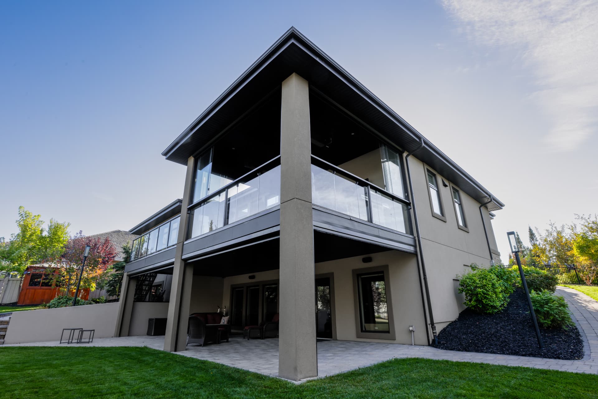 Rear elevation of a two-storey home with the glazed upper balcony above a covered patio