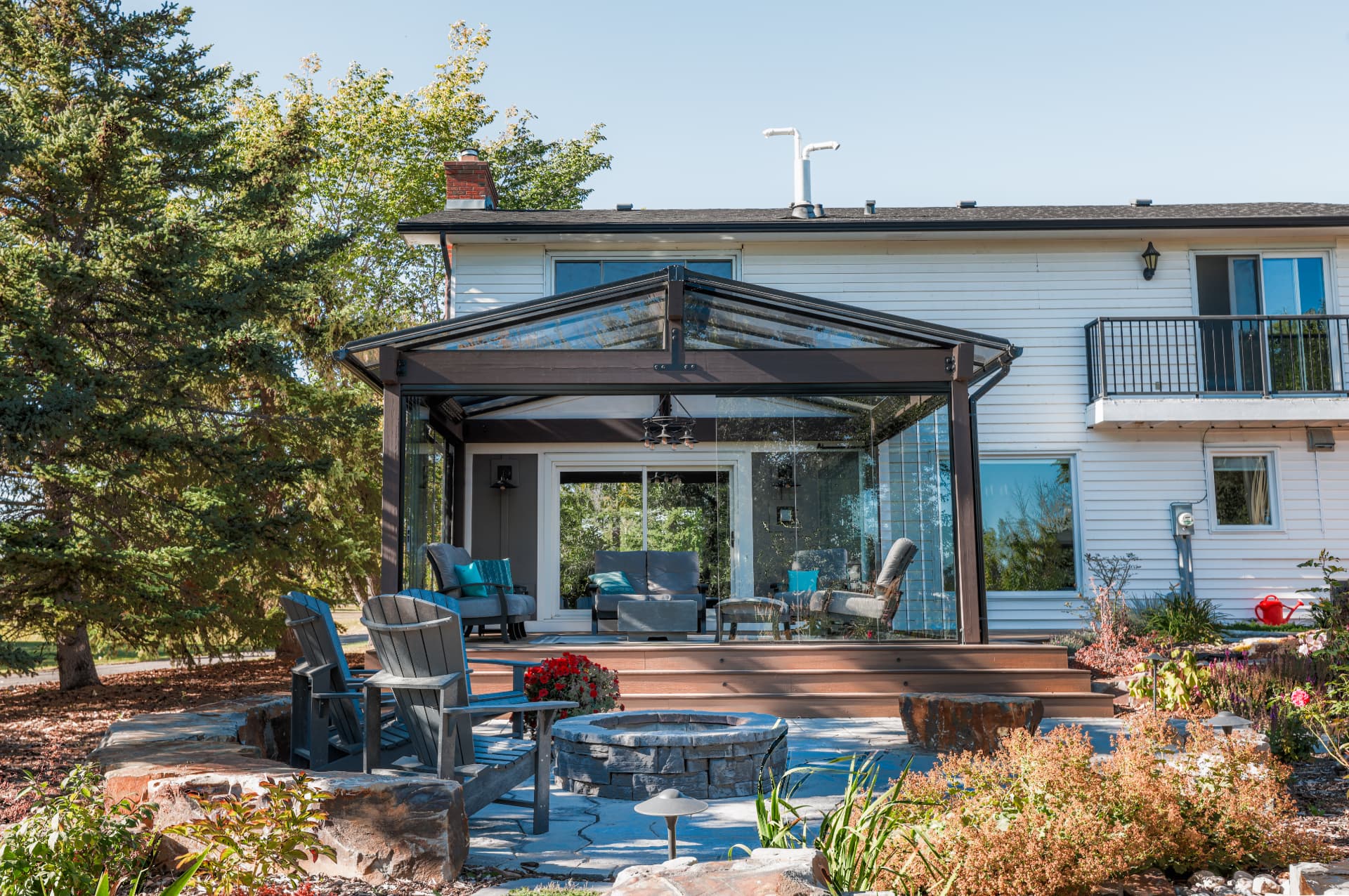 Rear elevation of the house with the glazed patio enclosure and stone fire pit