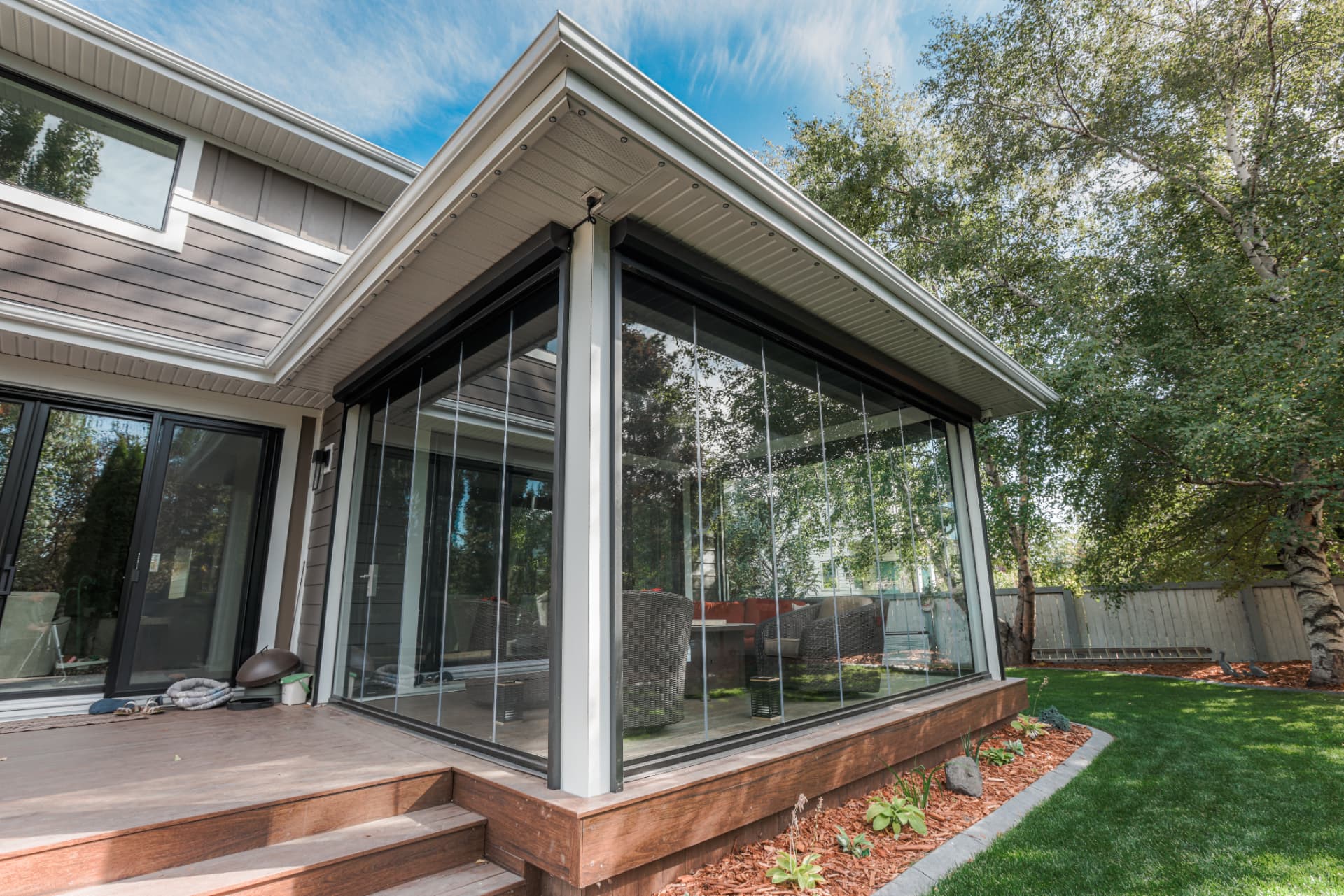 Corner view of the glass enclosure and deck steps from the garden