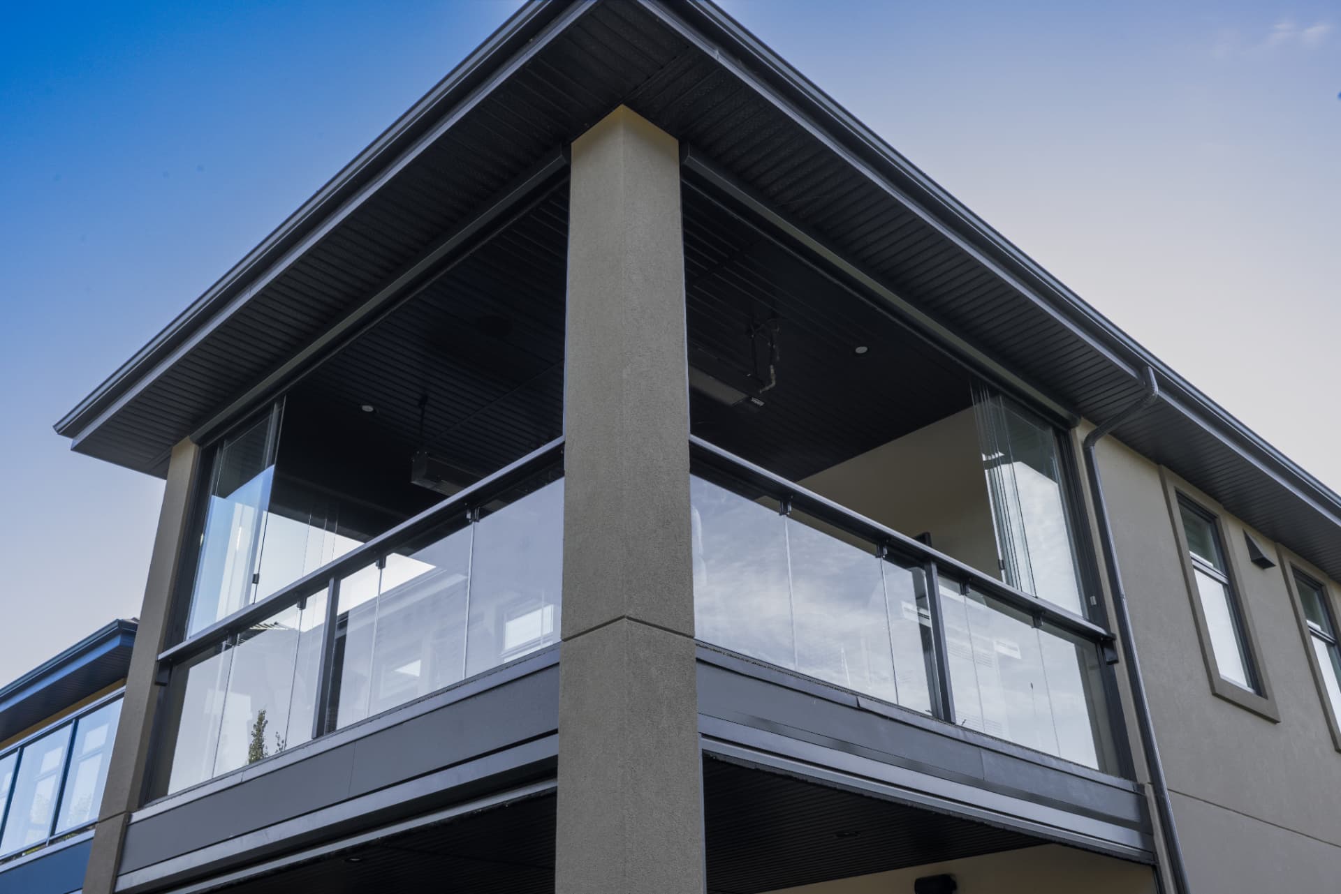 Corner detail of the retractable glass panels and glass railing on the upper balcony