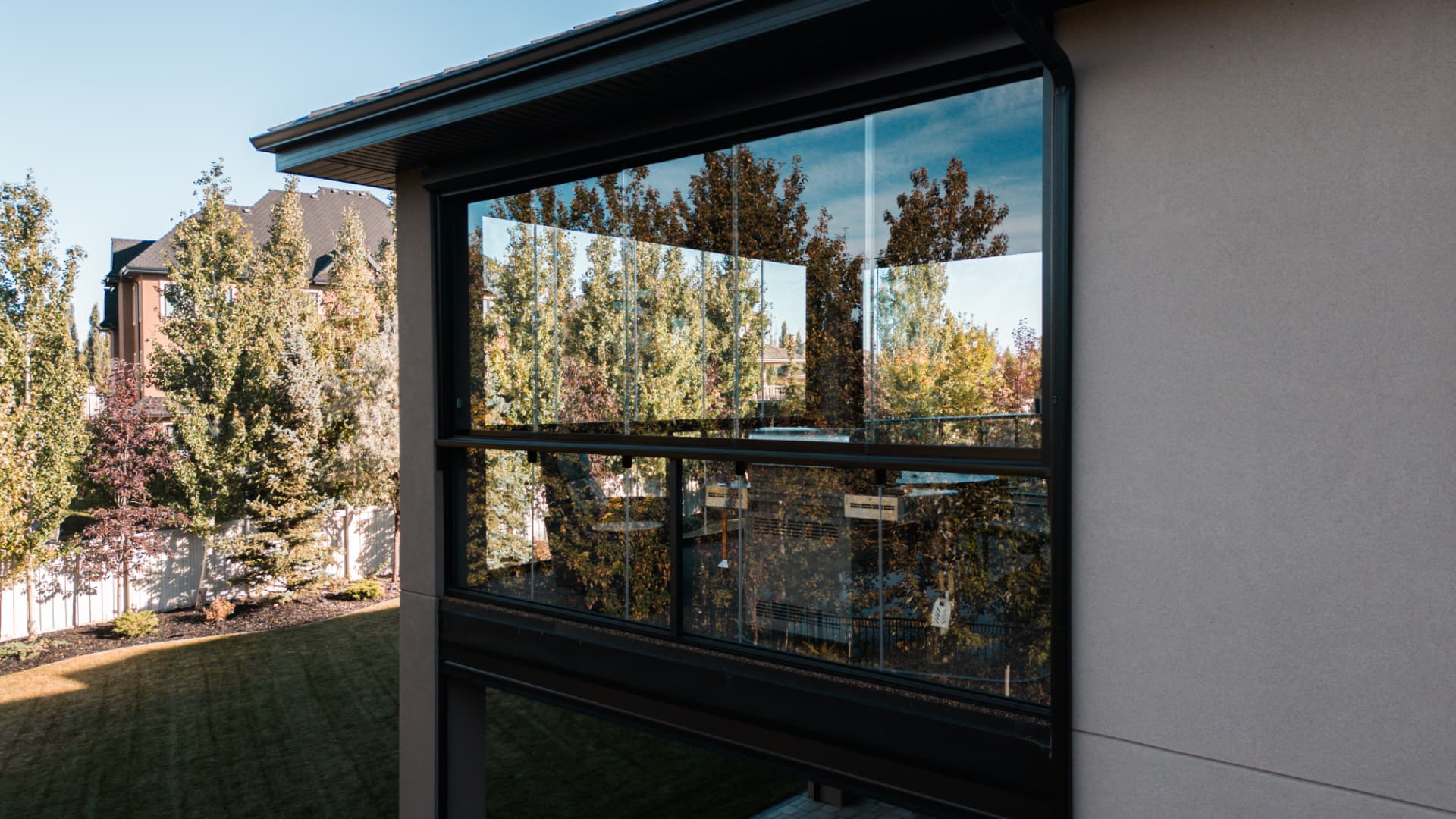 Close view of the frameless glass panels and motorized screen housing along the balcony