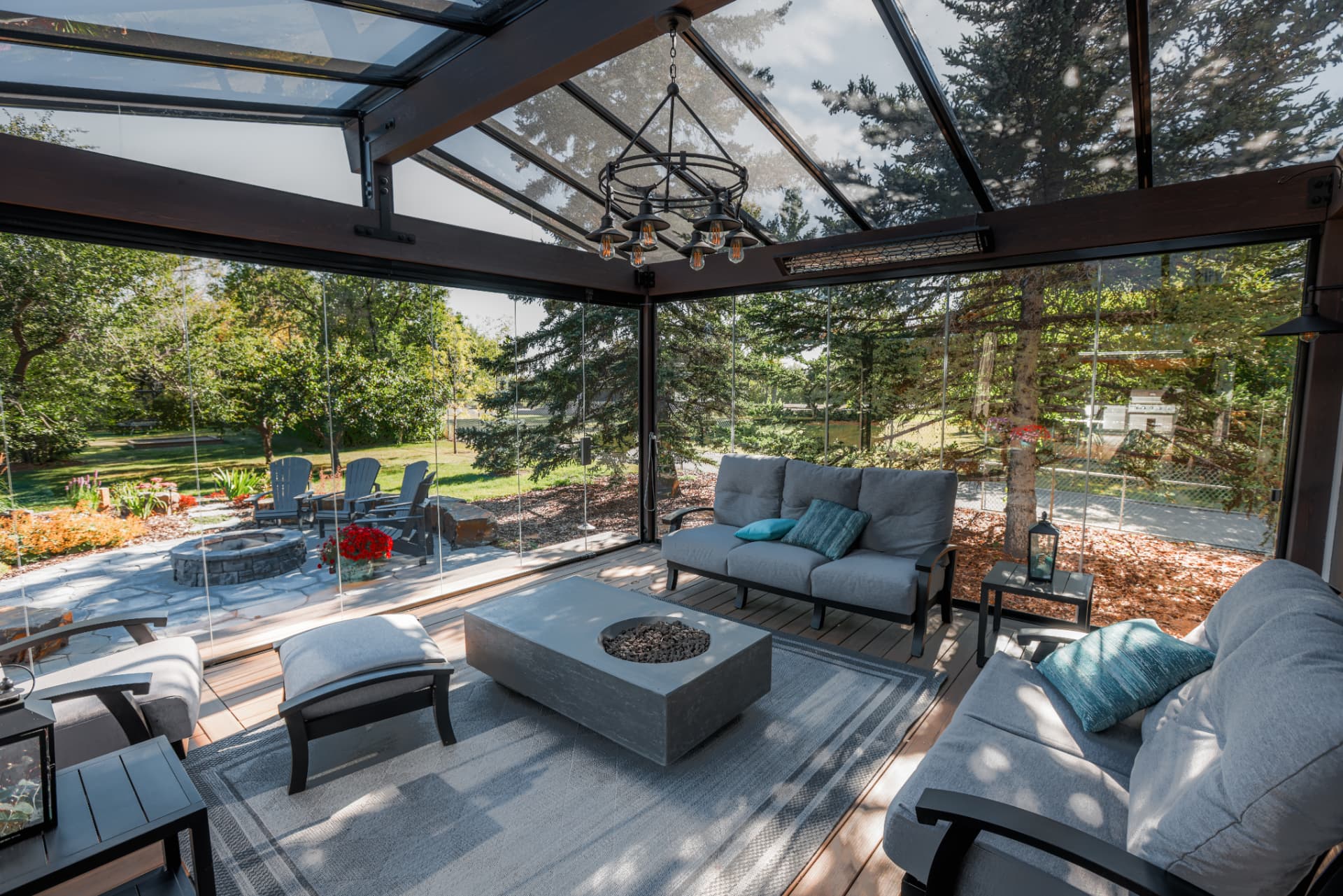 Interior of the glass room with fire table, lounge seating and a glass gable roof