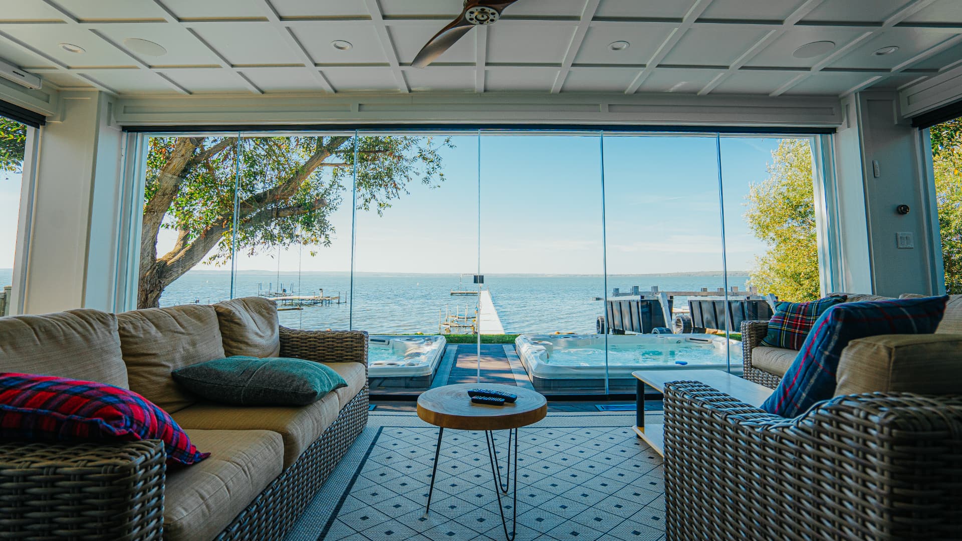 Lakeside glass room interior with wicker lounge seating looking out over the water
