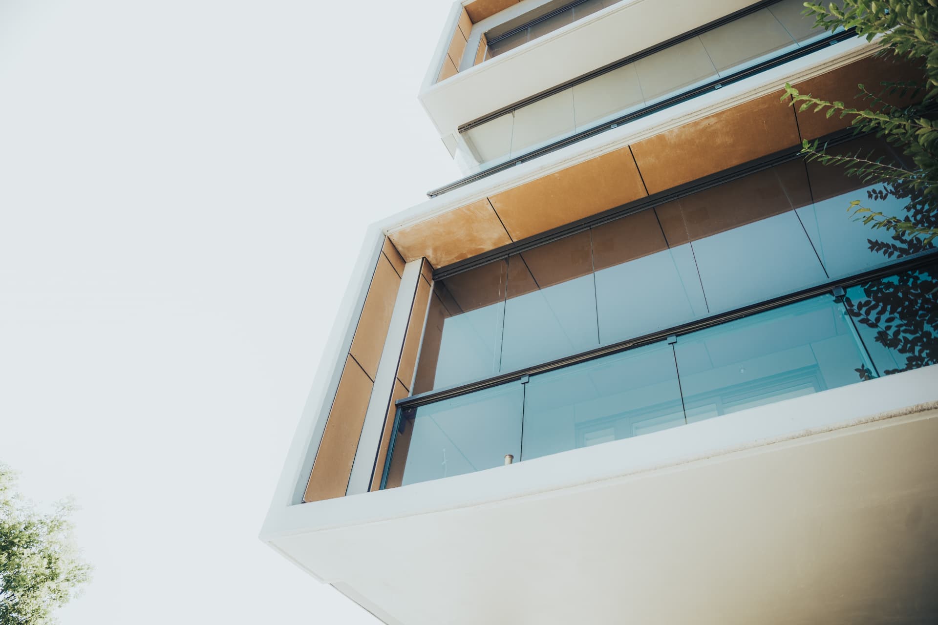 Looking up at stacked balconies with frameless glazing above glass railings